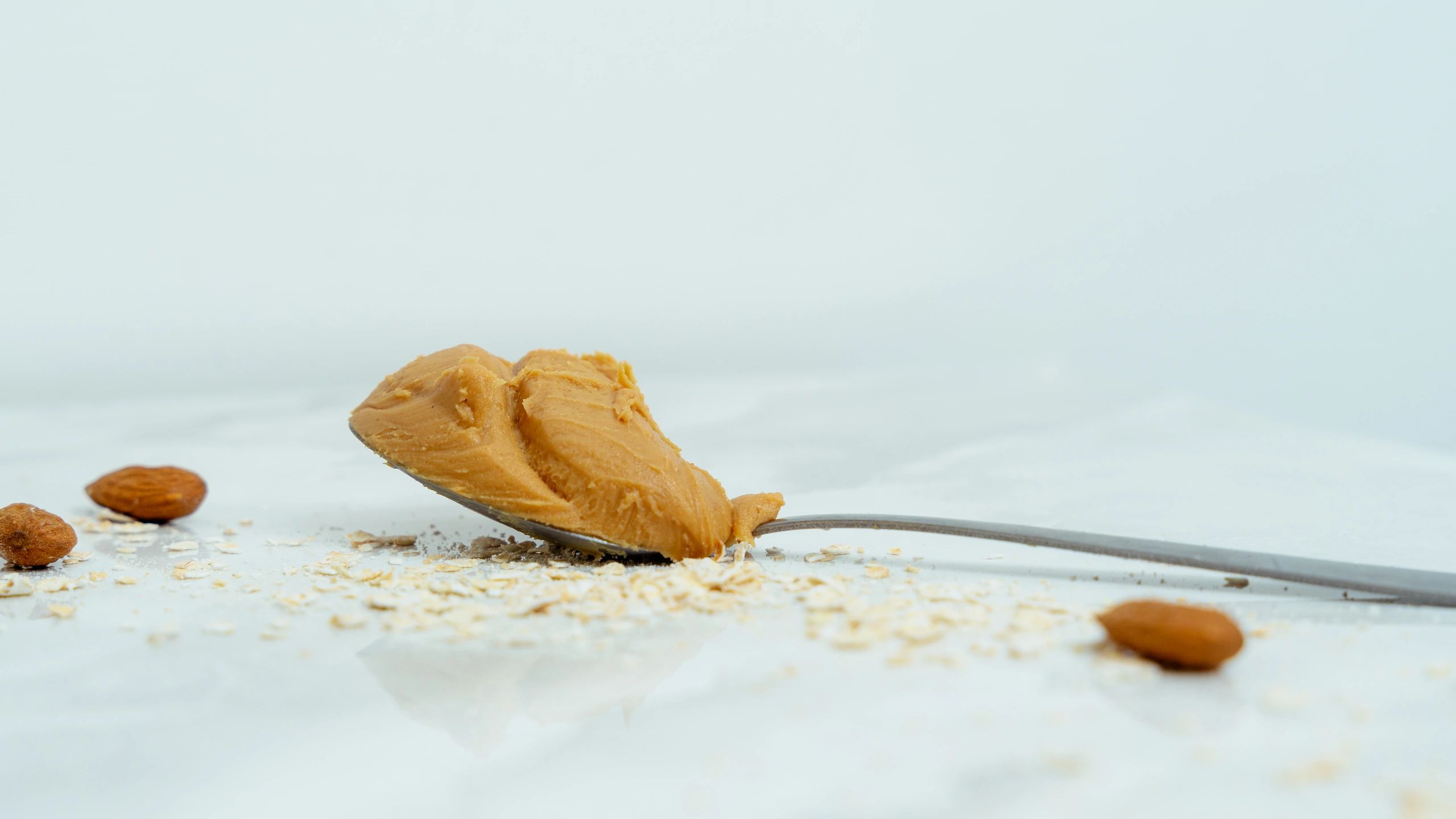Spoonful of creamy peanut butter with almonds and oats